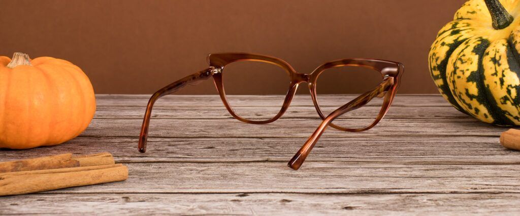 Brown cat-eye Ted Baker frames on a wooden surface with pumpkins in the background