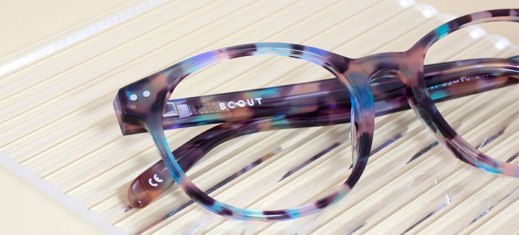 A round acetate frame with a colourful marble pattern that includes brown, blue and green