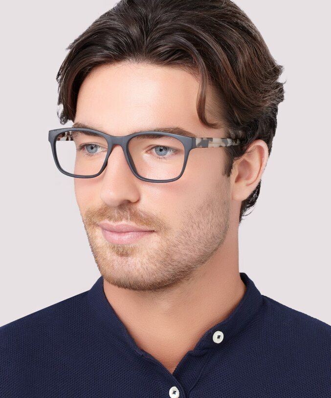 A man wearing a dark-blue shirt and The Collection Aero acetate rectangular glasses with tortoiseshell temples, on a white background.