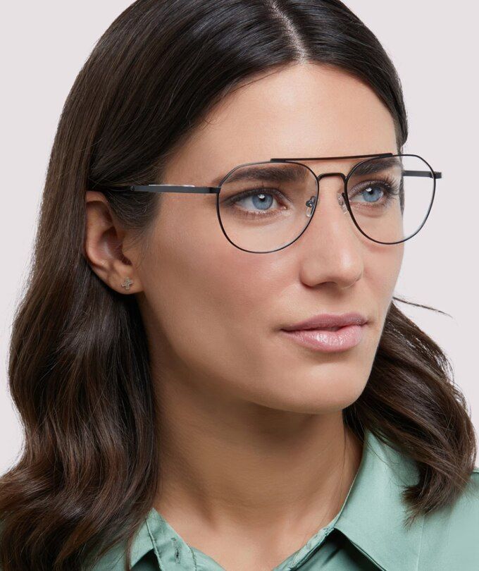 A woman with dark hair wearing a light green blouse and The Collection Colby large aviator black metal glasses.
