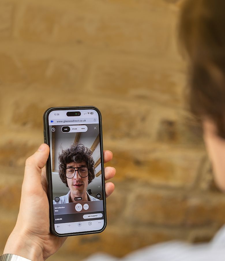A man looking at the virtual preview of himself wearing glasses on his phone