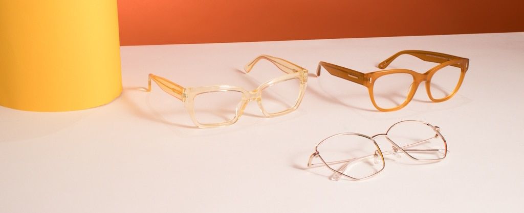 Three frames ranging from pale yellow to orange to gold lying on a white table next to a yellow pillar