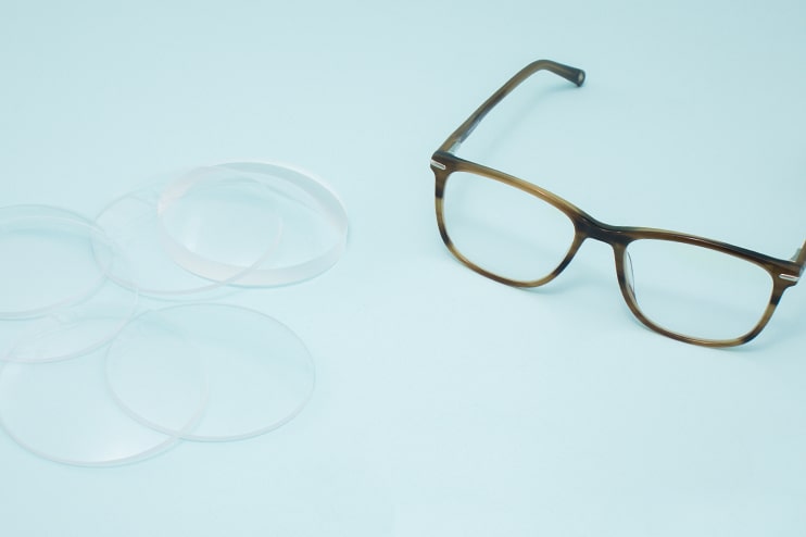 A pair of glasses and several lenses lying on a table