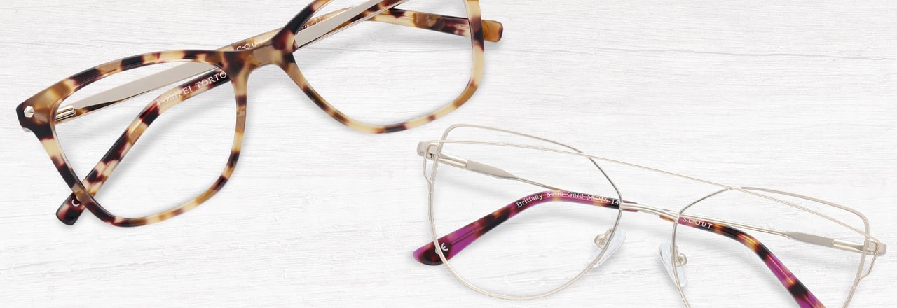 A tortoiseshell cat-eye frame and and an angular silver glasses frame with purple temple tips lying next to each other