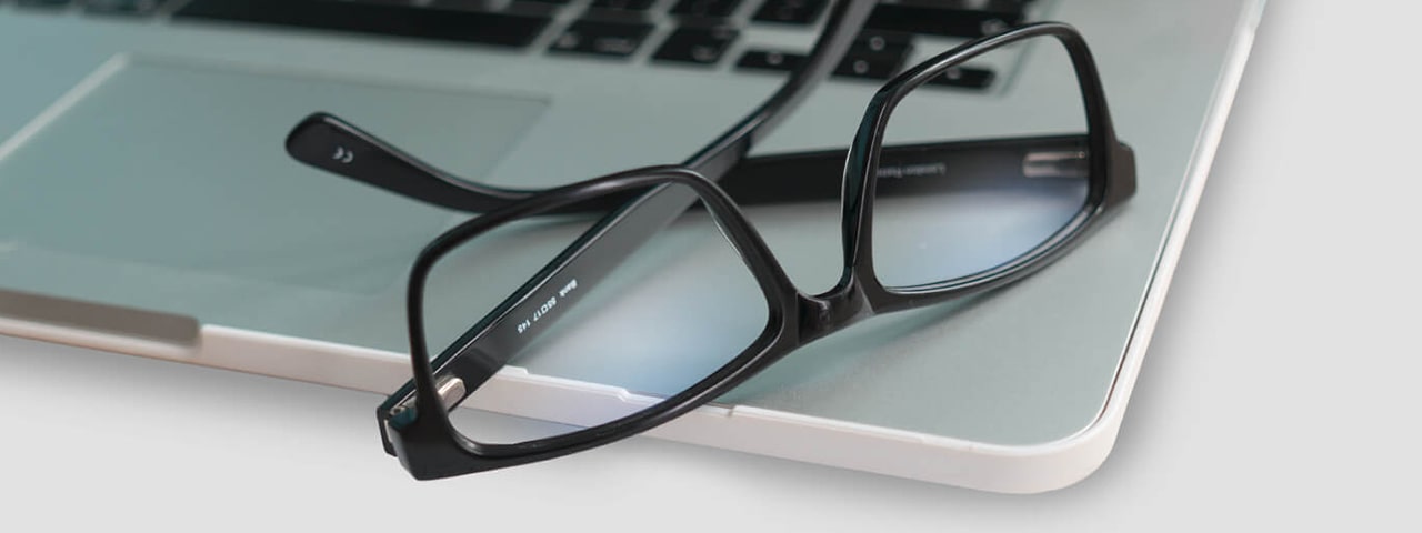 Black glasses lying on a laptop