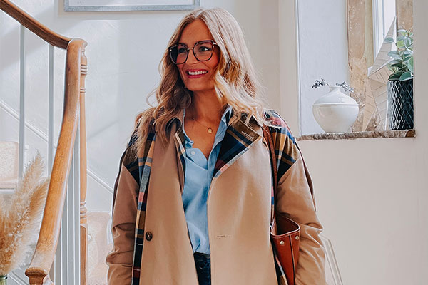 Smiling woman with glasses walking down stairs in her home