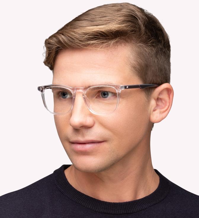 A man with short blond hair that is longer at the top than on the sides of his head, wearing New Balance NB4164 glasses