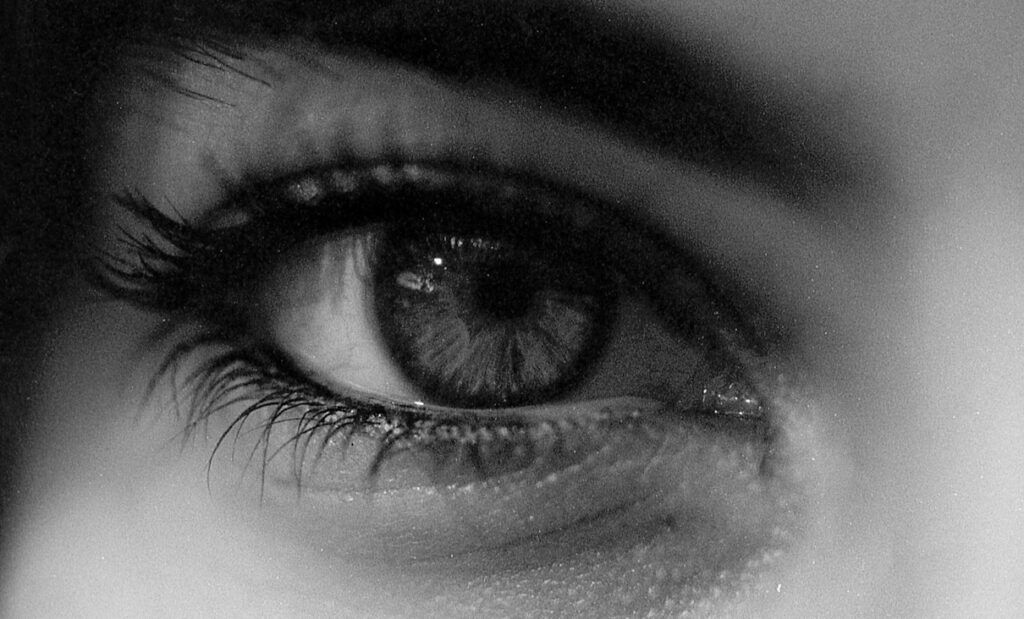 Extreme close-up of a grey human eye in greyscale.